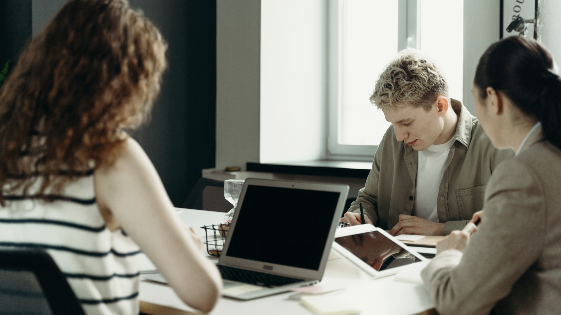 Group of young real estate agents sitting with laptops open using their real estate CRM software to connect with clients