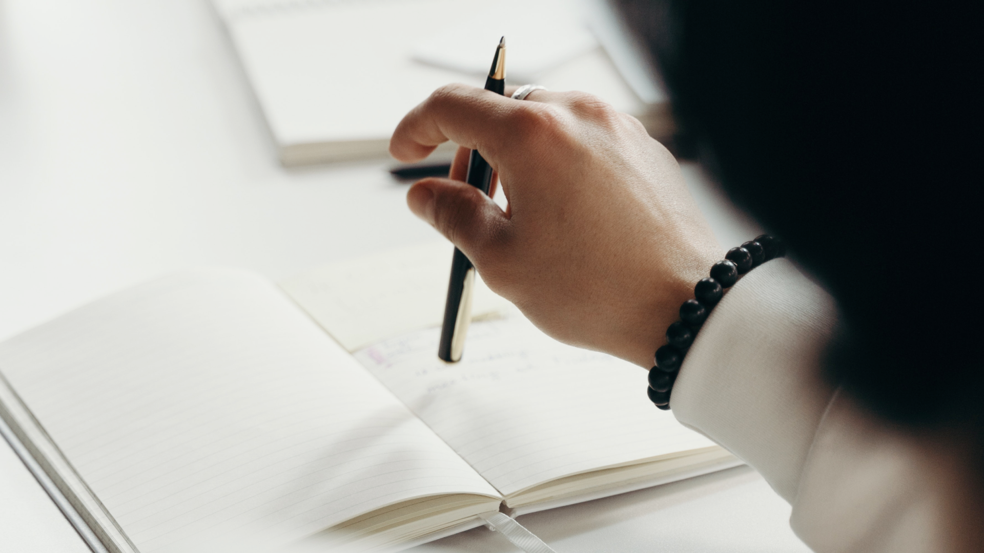 hand holding pen hovering over open notebook