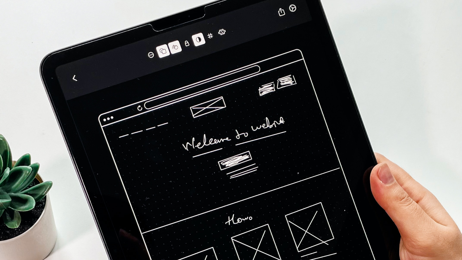 Hand holding tablet with website wireframe pulled up 